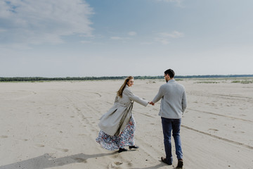 A young woman and a man walk, hug and kiss in a sand quarry.