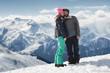 © guruXOX - Romantic snowboarder couple embracing on snow, with beautiful Alps mountain range in background. Love concept. Winter holiday scenic