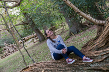 Smiling Woman Sitting On A Large Trunk Of A Fallen Tree In The Sherwood Forest