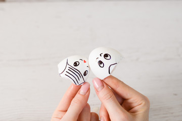 Female hand hold eggshells with drawn faces