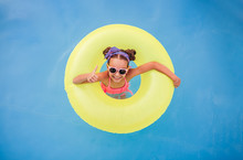 Positive Kid With Float Gesturing Thumb Up In Pool