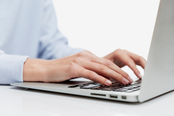 Hands of a young girl on a laptop keyboard. Education, work and blogging. Close-up. White background.