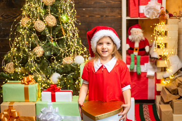 Cheerful cute child opening a Christmas present. Happy child decorating Christmas tree. Cute little child near Christmas tree.