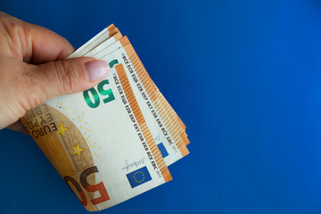 50 Euro banknote in hand on a bright blue background. The concept of cash