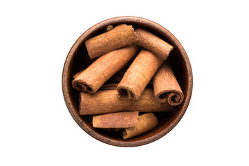 Wall Mural - cinnamon sticks spice in wooden bowl, isolated on white background. Seasoning top view