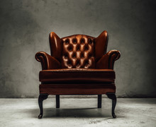 Luxorious Brown Leather Vintage Armchair Standing In A Dark Studio