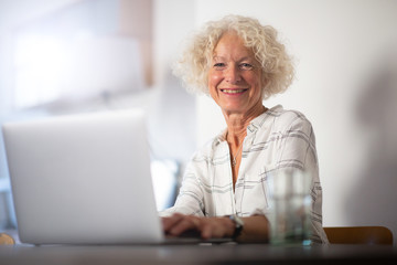 happy old woman sitting with laptop computer
