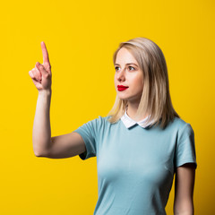 Wall Mural - Smiling blonde girl in blue dress on yellow background