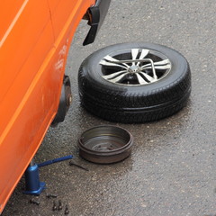 Wall Mural - Repair of the brake mechanism of the rear axle, the removed wheel and the brake drum are lying on the road next to the car on a hydraulic Jack