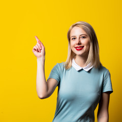 Wall Mural - Smiling blonde girl in blue dress on yellow background