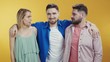 © Fractal Pictures - Caucasian young couple of lovers holding hands posing on background. Third wheel jealous bearded friend embracing separating man and woman. Love triangle.