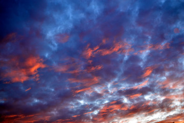 Blue red sunset sky with illuminated clouds