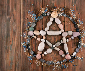 Pentagram made of stones with dry flowers of gypsophila on a wooden background. Top view.