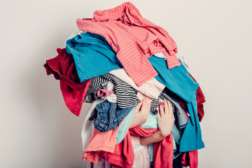 Mommy little helper. Cute Caucasian girl sorting clothes. Adorable funny child arranging organazing clothing. Kid holding messy stack pile of clothes, things. Home chores housework.