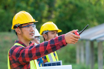 Wall Mural - Group of engineer working on checking and maintenance with solar batteries near solar panels at sunny day in solar power plant station.