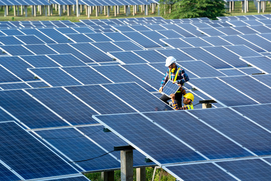Group of engineer working on checking and maintenance with solar batteries near solar panels at sunny day in solar power plant station.