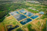 Fototapeta Natura - Artificial pond, for maintenance and purification of water from sewage. Water storage for purification from impurities. Urban water treatment in clusters. Reflections sky in mirror water. Aerial view