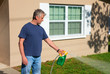 © Michael O'Keene - Homeowner man spraying weed killer on the grass on grass in his yard with hose attachment full of chemicals