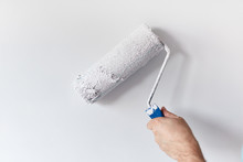 Left Hand Man's Hand Painting The Wall With Paint Roller. Painting Apartment, Renovating With White Color Paint