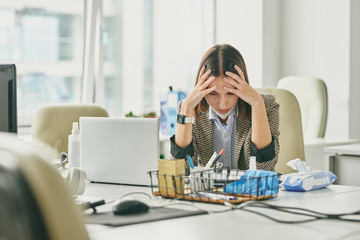 Aufkleber - Puzzled young office woman sitting at desk in empty office during coronavirus epidemic and holding head in hands while having problems