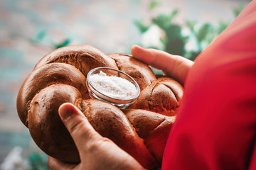 Wedding bread with salt for a meeting of newlyweds. Russian wedding tradition to meet newlyweds with bread and salt. Appetizing delicious wedding loaf with salt in women's hands.