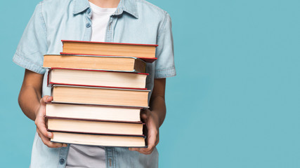 Close-up boy holding stack of books