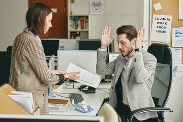 Wall Mural - Assistant showing contract to manager and explaining contractual obligations in front of partnership company to him, manager annoyed by situation