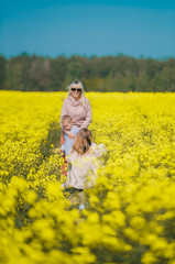 Wall Mural - Happy family of three together at meadow outdoor. Bright Yellow rapeseed oil.