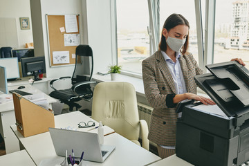 Aufkleber - Young office woman in cloth mask scanning document in empty office during coronavirus epidemic