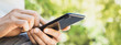 © kite_rin - Young man texting on his smartphone in the city. Close up of adult male hand using mobile phone outdoor, panoramic banner