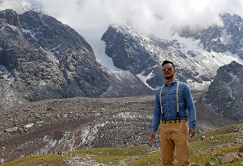 man with aviator sunglasses in front of a mountain panorama