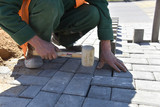 Fototapeta  - A bricklayer levels paving slabs with a hammer.