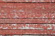 Old peeling paint of red color on a wooden background