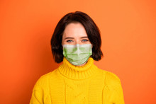 Photo Of Cute Nice Good Friendly Charming Girl Stay Home Covid-19 Self-isolation Stop Epidemic Wear Fabric Mask Isolated With Orange Background