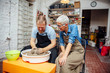 © BGStock72 - Senior woman spinning clay on a wheel with teacher at pottery class