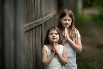 tender young girls children pray near a wooden fence, intimacy and openness, trust between sisters. 