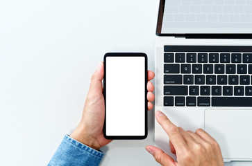 Aufkleber - Using smart phone from above. White blank screen. Laptop on white background.