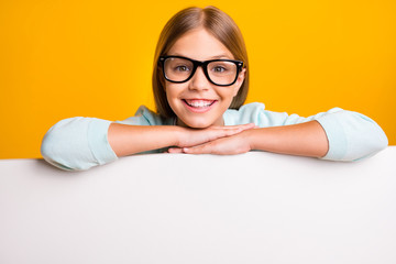 Closeup photo of beautiful little lady diligent student pupil hands leaning big empty space white placard banner presenting sales wear specs casual outfit isolated yellow color background