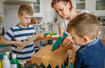 Canvas Print - Mom and kids making a cardboard dinosaur costume