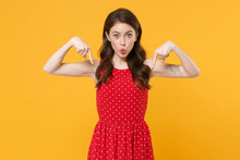 Amazed Young Brunette Woman Girl In Red Summer Dress Posing Isolated On Yellow Background Studio Portrait. People Sincere Emotions Lifestyle Concept. Mock Up Copy Space. Pointing Index Fingers Down.