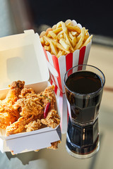Wall Mural - deep fried chicken, french fries and soda in glass on glass table in sunlight