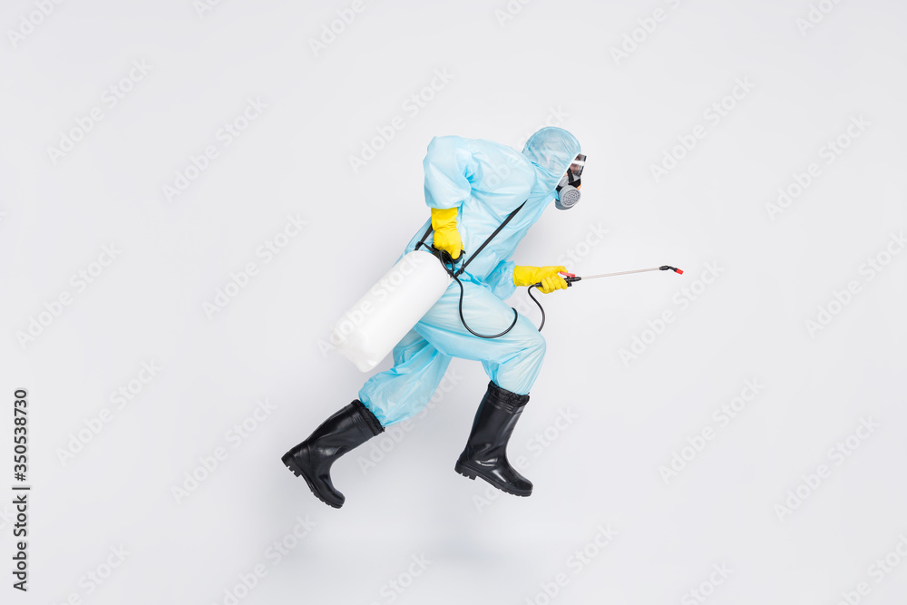 Full body profile side photo man jump run hurry disinfect covid spread house wear white hazmat suit yellow rubber latex gloves goggles use sprayer isolated gray color background - obrazy, fototapety, plakaty 