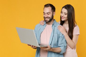 Sticker - Smiling young couple two friends guy girl in pastel blue casual clothes posing isolated on yellow wall background. People lifestyle concept. Mock up copy space. Working on laptop pc computer, hugging.