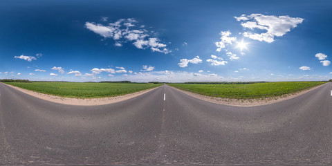 Wall Mural - Full spherical seamless panorama 360 degrees angle view on no traffic asphalt road among fields with cloudy sky in equirectangular projection, VR AR content