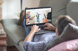 © GENETTICA - Man lying on the sofa using laptop with online courses on the screen