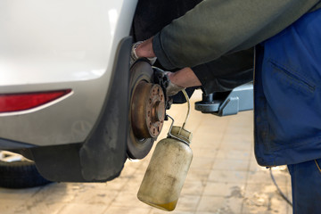 Wall Mural - Car repair in a car service. Replacing brake fluid on a vehicle. The brake disc and a special tool against the background of a repair shop.