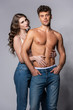 © LIGHTFIELD STUDIOS - woman touching sexy and muscular boyfriend standing with hands in pockets on grey