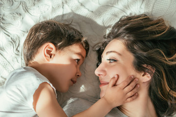  top view of cute toddler boy touching face of attractive mother