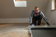 © artursfoto - Construction worker installing laminate floor in a new renovated attic. Home improvement concept.