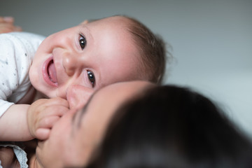 Wall Mural - Authentic  close up shot of an young happy neo mother is playing with her smiling newborn baby boy on a bed just woke up in a morning.  